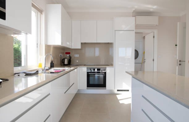 Brand new modern kitchen with white cabinets and beige stone counter top and ceramic tiled floor