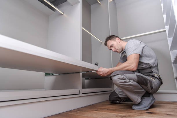 Caucasian Men in His 40s Assembling Elegant Modern White Closet Furnitures Inside His Apartment.